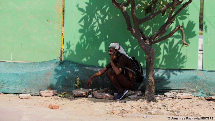 भारत की राजधानी दिल्ली में गर्मी से निजात पाने के लिए एक छोटे से पेड़ की छांव में बैठा मजदूर.