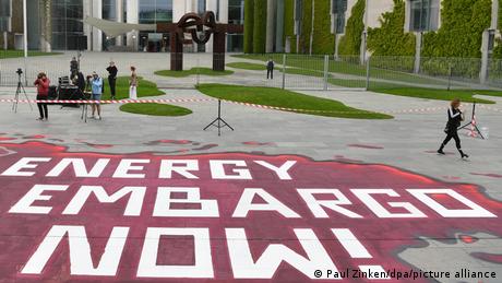 Auf dem Boden vor dem Kanzleramt steht in großen Buchstaben Energy Embargo Now!