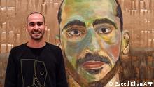 Artist Mostafa Azimitabar is pictured in front of his work, titled Self-Portrait, as the finalists' work for the Archibald Prize is displayed in Sydney on May 5, 2022. - Azimitabar was announced as a finalist for Australia's most esteemed art prize, just over a year after he was released from one of the country's notorious immigration hotels. (Photo by Saeed KHAN / AFP) / RESTRICTED TO EDITORIAL USE - MANDATORY MENTION OF THE ARTIST UPON PUBLICATION - TO ILLUSTRATE THE EVENT AS SPECIFIED IN THE CAPTION / “The erroneous mention[s] appearing in the metadata of this photo by Saeed KHAN has been modified in AFP systems in the following manner: [for the Archibald Prize] instead of [2022 Packing Room Prize]. Please immediately remove the erroneous mention[s] from all your online services and delete it (them) from your servers. If you have been authorized by AFP to distribute it (them) to third parties, please ensure that the same actions are carried out by them. Failure to promptly comply with these instructions will entail liability on your part for any continued or post notification usage. Therefore we thank you very much for all your attention and prompt action. We are sorry for the inconvenience this notification may cause and remain at your disposal for any further information you may require.”