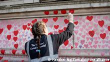 March 25, 2022, London, United Kingdom: A volunteer repaints a red heart on the national COVID memorial wall. Volunteers re-paint the hearts on the national COVID memorial wall every Friday as the previous hearts faded due to the weather. Over 150,000 hearts have been painted to date on the wall outside St Thomas' Hospital opposite the Houses of Parliament to commemorate each life lost in the UK due to the COVID pandemic since 2019. (Credit Image: © Hesther Ng/SOPA Images via ZUMA Press Wire