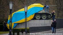 Polizeibeamte entfernen die Flagge der Ukraine von einem historischen Panzer am Sowjetischen Ehrenmal an der Straße des 17. Juni. Zuvor war der Panzer in die ukrainische Flagge gehüllt. (Zu dpa Sowjetisches Ehrenmal ohne Panzer? Senatorin weist Vorstoß zurück) +++ dpa-Bildfunk +++