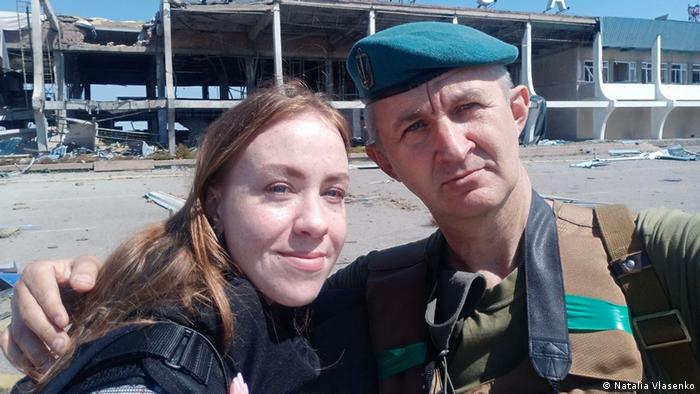 Travel guide Natalia Vlasenko and a soldier in front of a destroyed airport in Mykolaiv