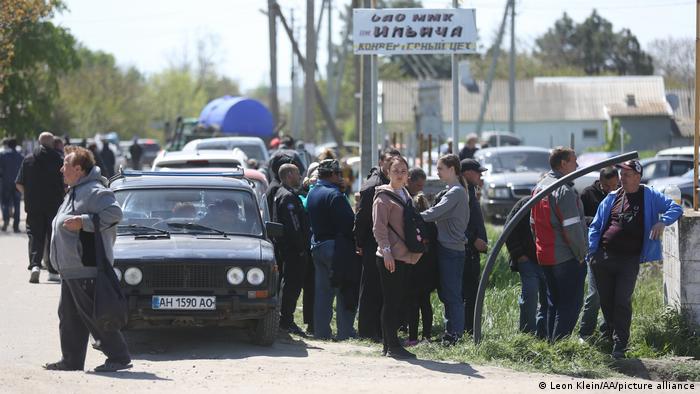 Several dozen Ukrainian civilians stand around a car