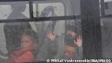 Kinder in einem Bus, die durch die verschmutzte Scheibe schauen. Ein kleines Kind mit Schnuller drückt die Hände gegen die Scheibe