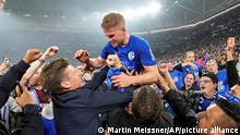 Schalke's scorer Simon Terodde is celebrated on the shoulders of fans who stormed the pitch to celebrate the team's promotion to the Bundesliga after the 2nd Bundesliga soccer match against FC St. Pauli at the Arena in Gelsenkirchen, Germany, Saturday, May 7, 2022. Traditional club FC Schalke 04 has secured an immediate return to the German top league after a 3-2 win over St. Pauli guaranteed a top-two finish in the 2nd division. (AP Photo/Martin Meissner)