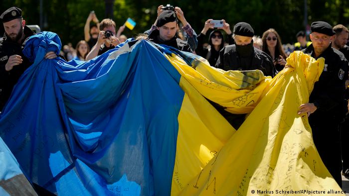 German police officers remove a huge Ukrainian flag from the side of a Soviet War Memorial at the district Tiergarten during commemorations to celebrate the end of World War II 77 years ago, in Berlin, Germany, Sunday, May 8, 2022