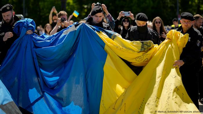 German police officers remove a huge Ukrainian flag from the side of a Soviet War Memorial at the district Tiergarten during commemorations to celebrate the end of World War II 77 years ago, in Berlin, Germany, Sunday, May 8, 2022