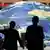 Two delegates to the World Summit on Sustainable Development walk in front of a giant globe in Sandton Square, adjacent to the Sandton Convention Centre in Johannesburg, South Africa, Monday Aug. 26, 2002. (AP Photo/Jon Hrusa)