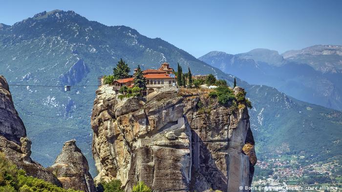 The Holy Trinity Monastery on top of a large rock with mountains in the background