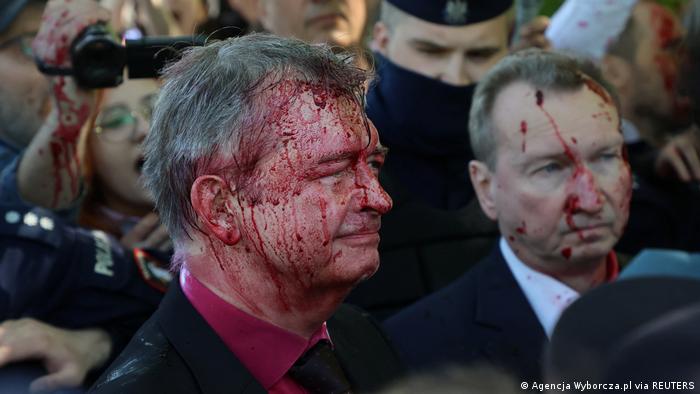 Russia's ambassador to Poland Sergey Andreev is covered in red substance thrown by protesters in Warsaw, Poland