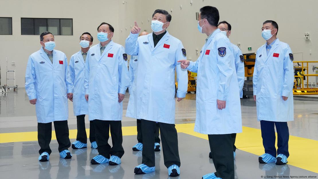 Presidente da China, Xi Jinping, com jaleco branco e máscara, junto de outros homens de jaleco branco