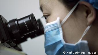 Китайский ученый смотрит в микроскоп