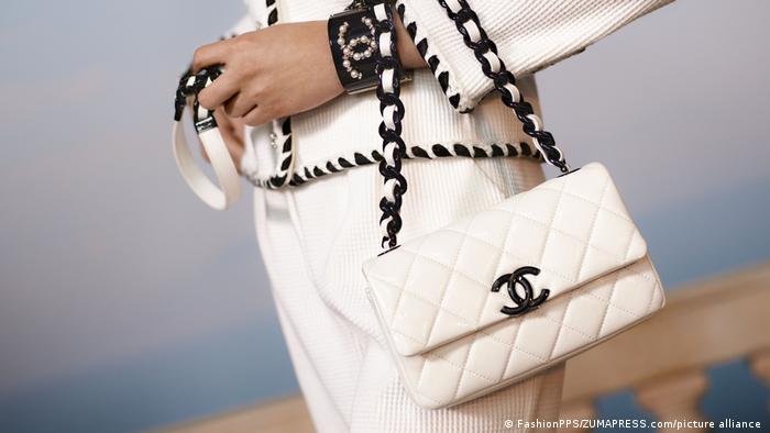 Woman holding a quilted white Chanel handbag