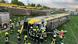 Rescue workers crowd around a train that lies on its side after coming off the railway tracks Rescue workers crowd around a train that lies on its side after coming off the railway tracks