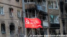 A Soviet-era flag, which was raised to mark the anniversary of the victory over Nazi Germany in World War Two, flies in front of a residential building heavily damaged in the course of Ukraine-Russia conflict in the southern port city of Mariupol, Ukraine May 8, 2022. REUTERS/Alexander Ermochenko