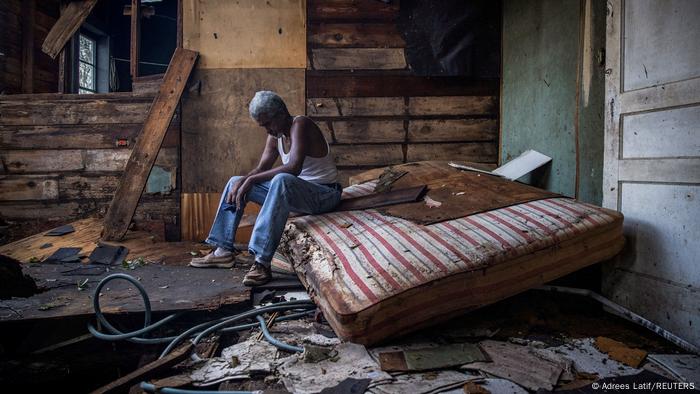 A man sits in his house destroyed by Hurricane Ida.