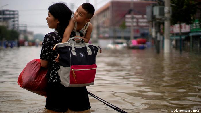 A woman carries her child through the flooded streets of the Chinese city of Zhengzhou.
