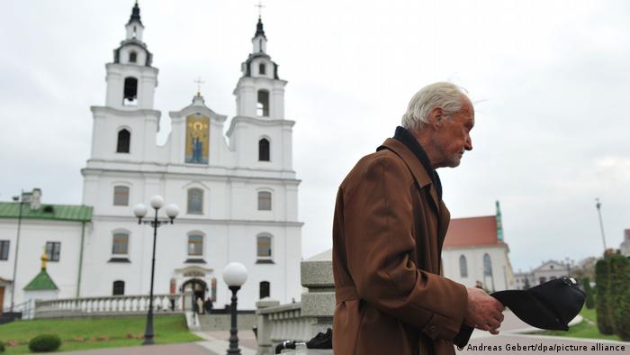 Пожилой мужчина просит милостыню у храма в Минске