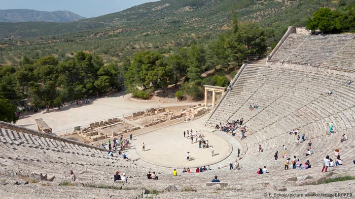 The great ancient amphitheater of Epidaurus overlooking forest and a mountain.