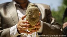 Un hombre muestra una estatuilla de piedra recién descubierta que data del 2500 a.C. y que representa el rostro de una antigua diosa en un museo de la ciudad de Gaza.