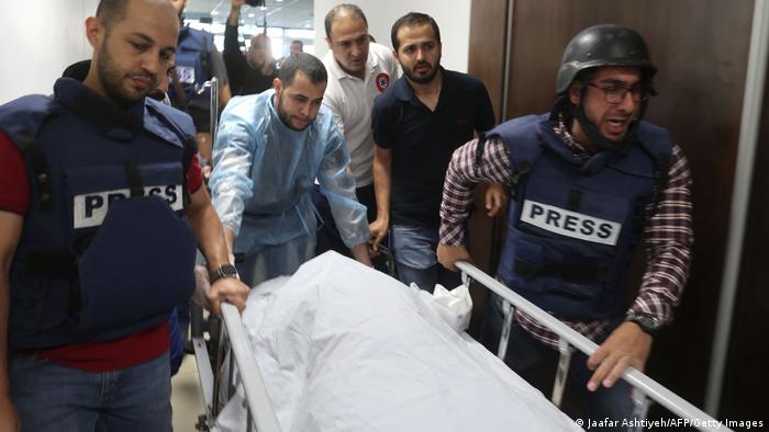 Journalists and paramedics push a bed with Shireen Abu Akleh's body on it