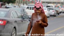 9.12.2019, Riad, Saudiarabien, A man smokes a cigarette as he watches his mobile in Riyadh, Saudi Arabia, Monday, Dec. 9, 2019. (AP Photo/Amr Nabil)