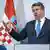 Kroatiens Präsident Zoran Milanovic während einer Rede mit erhobener rechter Hand. Im Hintergrund die kroatische Flagge.  