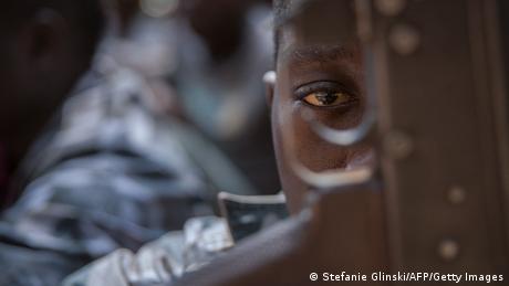  A newly released child soldier looks through a rifle trigger guard.