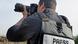 A journalist wearing a press vest holding a camera with a gigantic telephoto lens A journalist wearing a press vest holding a camera with a gigantic telephoto lens
