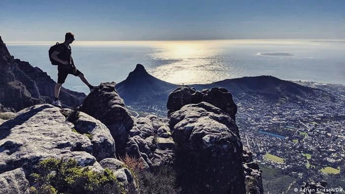 Ein Mann steht auf dem Tafelberg mit Blick auf Kapstadt