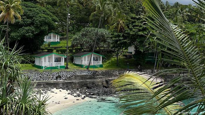 Houses next to a sandy beach with bright blue water on Comoros