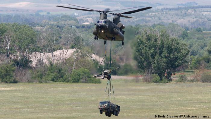 A helicopter transports a howitzer and a truck during a military exercise in North Macedonia on Thursday, May 12, 2022