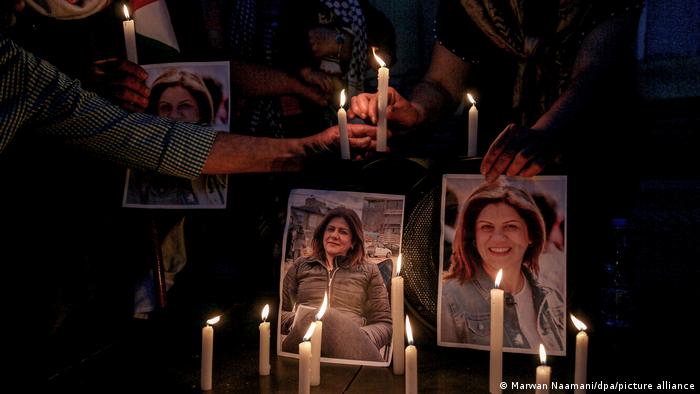 People hold candles at a memorial for the late journalist Shireen Abu Akleh