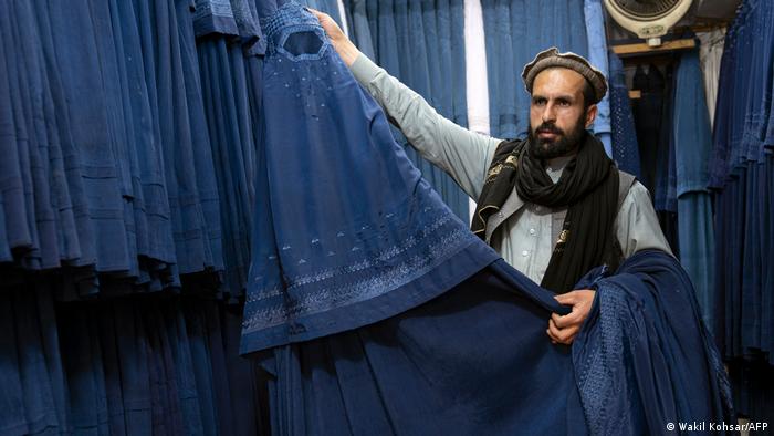 A burqa trader in Kabul presents his wares.