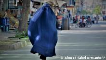 A burqa-clad woman walks along a street in Kabul on May 7, 2022. - The Taliban on May 7 imposed some of the harshest restrictions on Afghanistan's women since they seized power, ordering them to cover fully in public, ideally with the traditional burqa. (Photo by Ahmad SAHEL ARMAN / AFP)