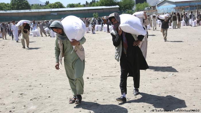Men in Kabul receive food deliveries from China and carry them away in sacks.