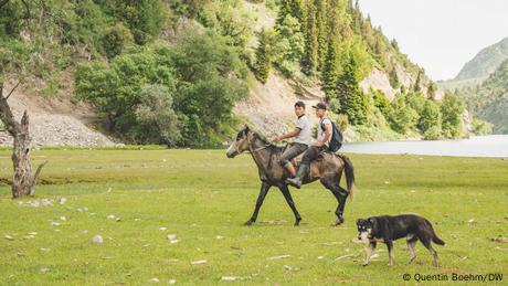 Zwei Teenager reiten auf einem jungen Pferd auf Weiden in der Region Jalalabad in Kirgisistan 