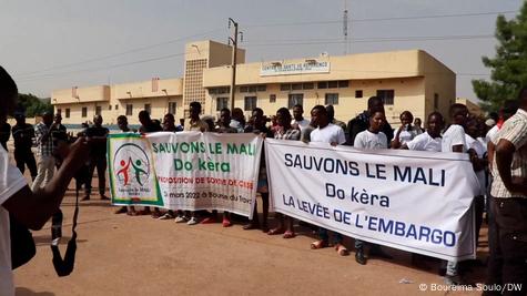 Des Maliens tiennent en main deux banderoles portant des messages demandant la levée des sanctions imposées contre leur pays (Archives - Bamako, 10.05.2022)