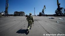 A Russian serviceman walks while guarding an area of the Mariupol Sea Port in Mariupol, in territory under the government of the Donetsk People's Republic, eastern Ukraine, Friday, April 29, 2022. This photo was taken during a trip organized by the Russian Ministry of Defense. (AP Photo)