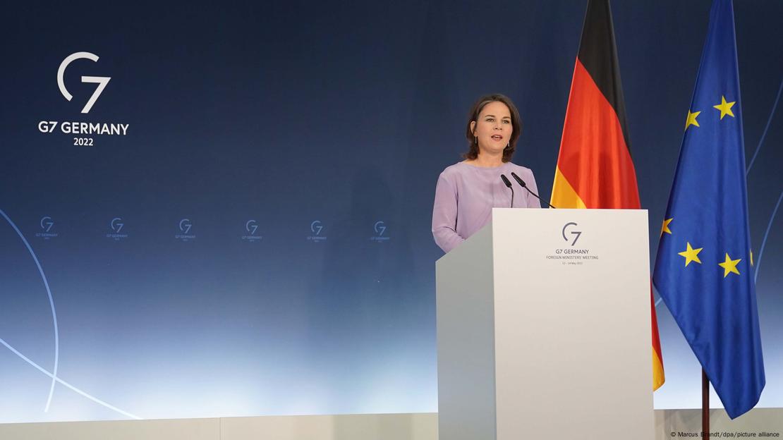 Annalena Baerbock discursa em palco com bandeiras de Alemanha e UE