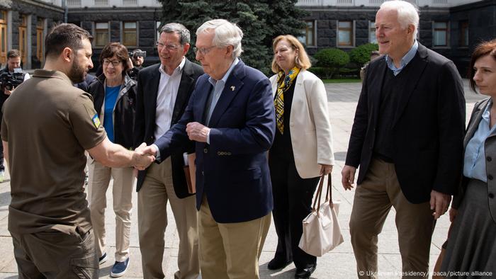 Ukrainian President Volodymyr Zelenskyy shaking hands with US Senate Minority Leader Mitch McConnell, other US lawmakers are visible