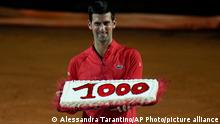 Serbia's Novak Djokovic holds a cake adorned with the number of his 1,000th tour-level win earned after winning his semifinal match against Norway's Casper Ruud at the Italian Open tennis tournament, in Rome, Saturday, May 14, 2022. (AP Photo/Alessandra Tarantino)