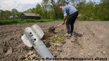 Local resident Ivan conducts agricultural work close to the detail of a rocket missile on his field in Lukashivka village, Chernihiv area, May 08, 2022 (Photo by Maxym Marusenko/NurPhoto)