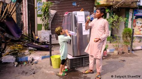 Two children drinking water from plastic bottles on street in India