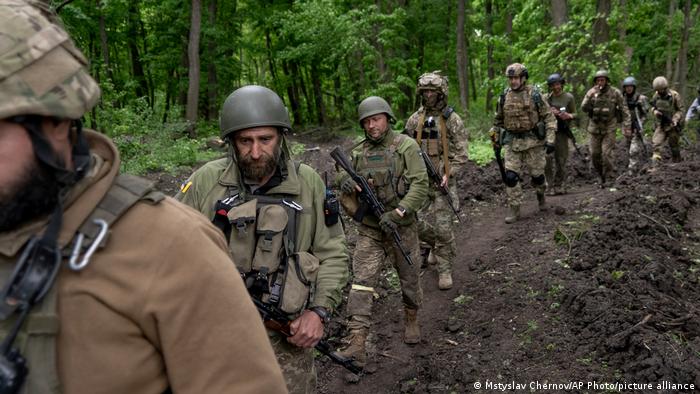 Ukrainian servicemen walk in the forest near a recently retaken village, north of Kharkiv
