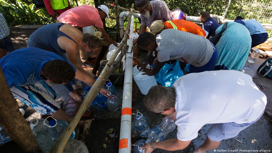 Residents fill containers with water at a source for natural spring water in Cape Town