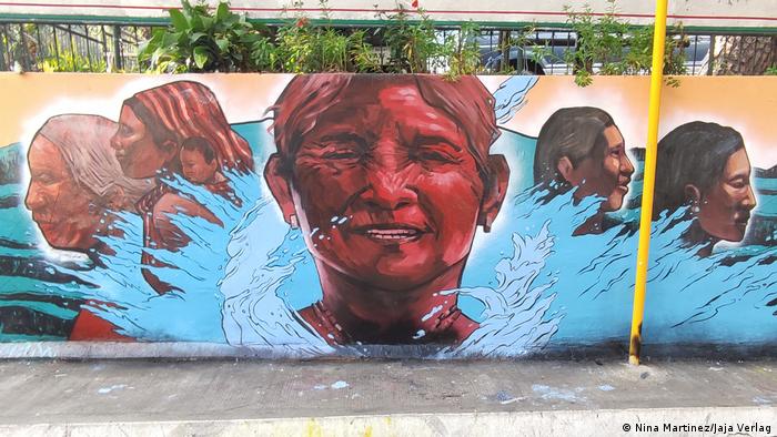 Mural of a smialing woman surrounded by other people and enclosed in a body of water