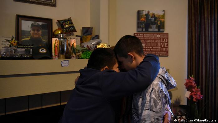 Aidan Garza, 12, (left) Julius Garza, 14, (right) and Margaret Garza pray together next to their father’s urn