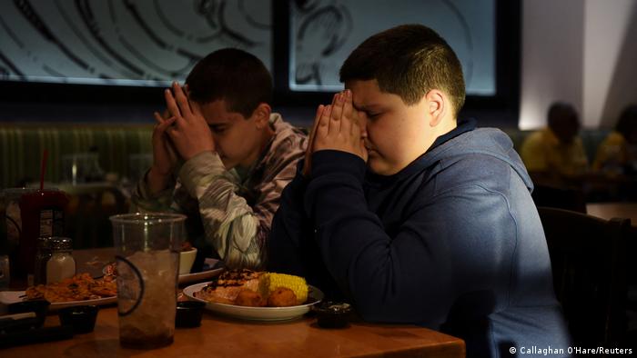 Brothers Julius Garza, 14, and Aidan Garza, 12, say a prayer in honor of their father, David Garza, who died from the coronavirus disease (COVID-19) in December 2020