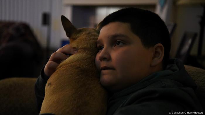 Aidan Garza hugs the family dog while watching television at home in Converse, Texas